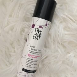 A bottle of hair spray sitting on top of a white fur.